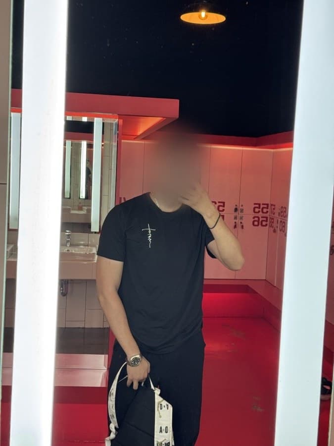 Mehdi today in a fitted black t-shirt in a red gym locker room, filled out at the chest and arms