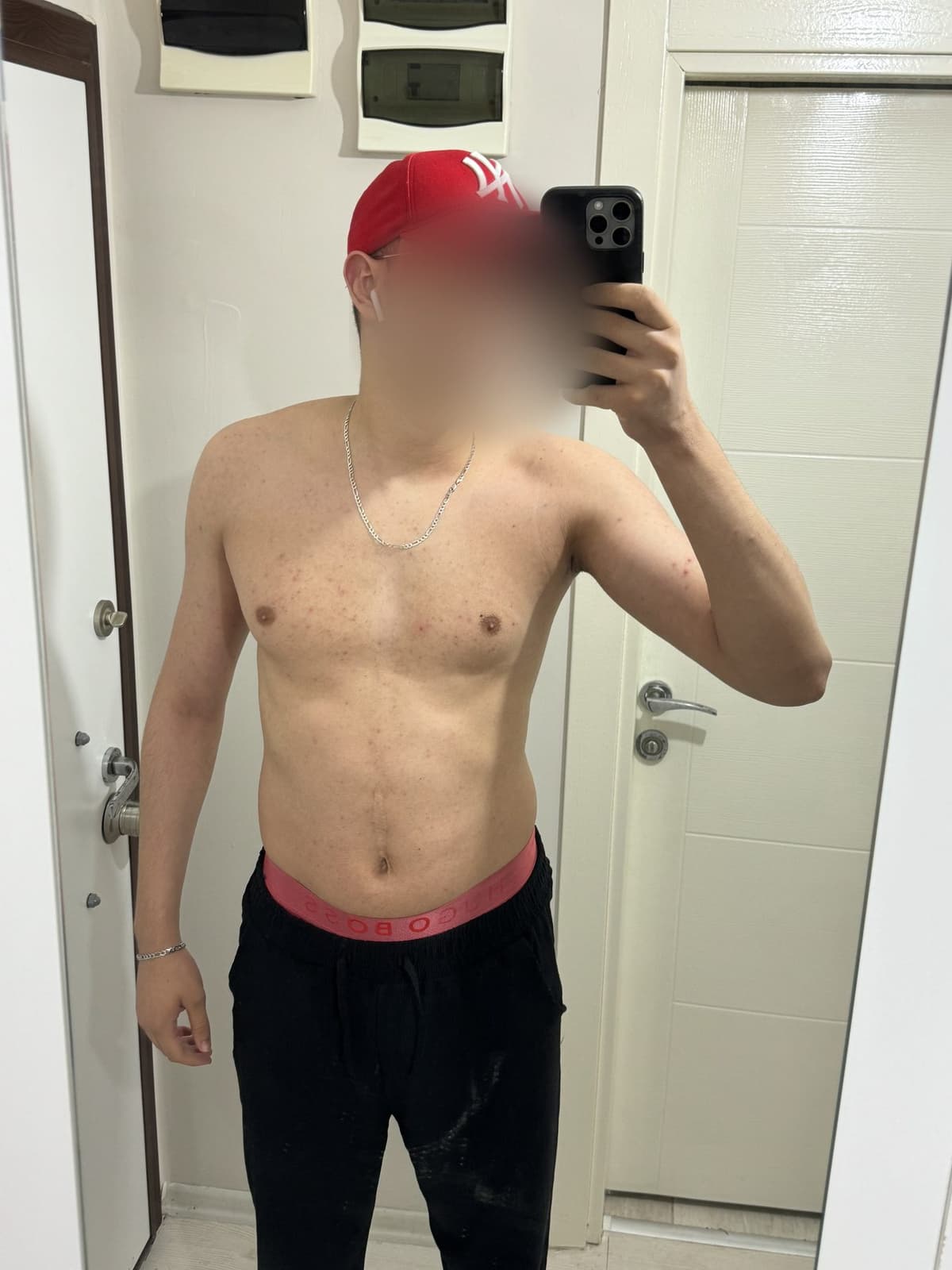 Month 4, shirtless mirror photo with a red cap, visibly bigger